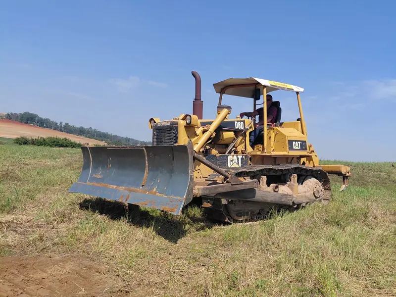 Trator de esteira Caterpillar D6 com lâmina trabalhando em terreno aberto